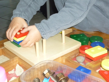 atelier Montessori chez nounou à Moingt assistante maternelle enfiler des pions sur les pics